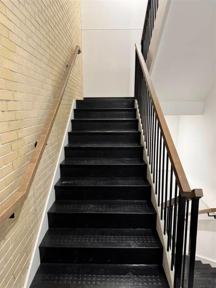 Escalier commercial, marches noires antidérapantes et rampes de bois
