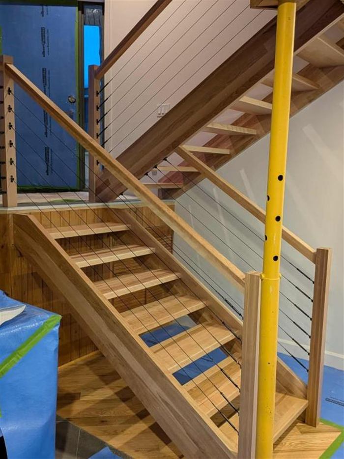 Escalier flottant en merisier avec garde-corps à câbles d'acier dans un chalet