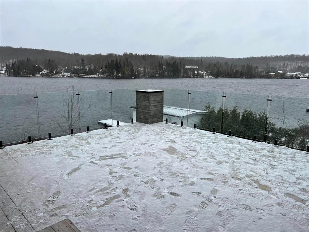 Terrasse sur le toit avec garde-corps de verre face à un lac