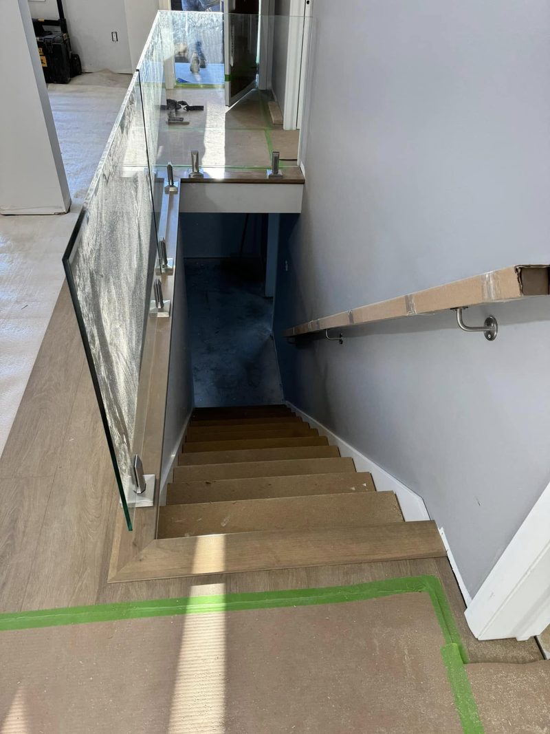 Escalier avec garde-corps de verre et rampe murale en bois