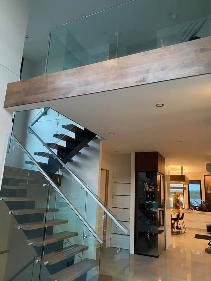 Escalier flottant à marches foncées et garde-corps de verre trempé sous une mezzanine